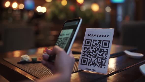 Scanning QR Code with Smart Phone. The Woman Reads the Bar Code Using the Application on the