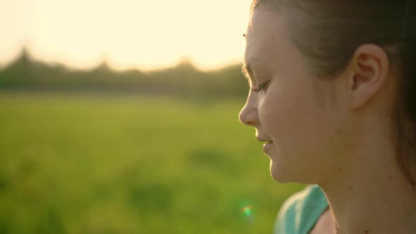 Closeup of a Young Happy Girl Blowing on a Dandelion alt
