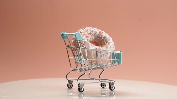 Sweet Donut in a Shopping Cart on a Cream Color Background