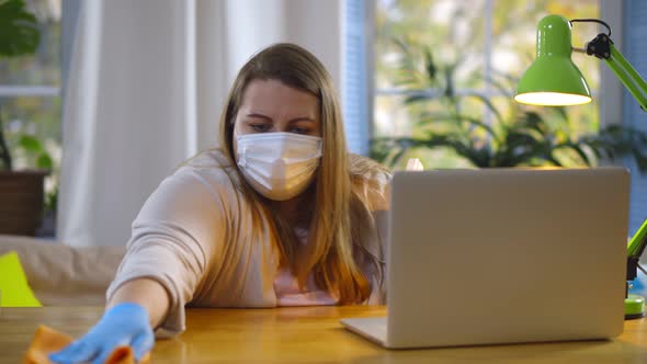 Obese Woman in Safety Mask Disinfecting Desk with Sanitizer Gel and Cloth Sitting at Home alt