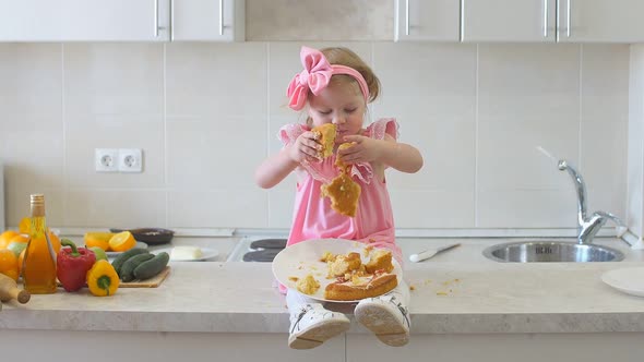 Cute Little Girl Eats Cake in The Kitchen.