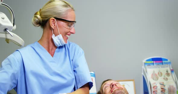 Female dentist giving high five to male patient alt