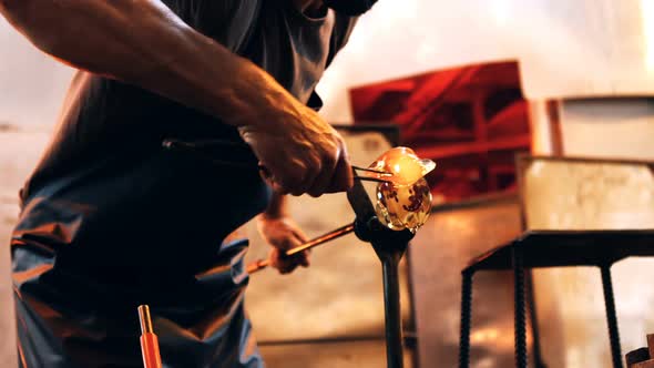 Glassblower shaping a molten glass alt