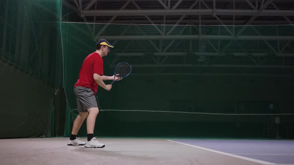 Young Handsome Man is Playing Tennis on Court Inside Stadium Striking Ball By Racquet Slow Motion alt
