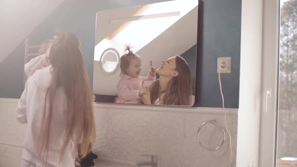 Lovely Mother with Little Family Brushing Teeth in Bathroom