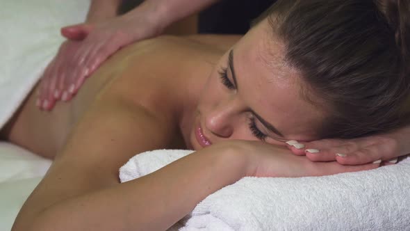 Close-up of the Face and Back of a Girl Who Has a Back Massage in the Spa Salon alt