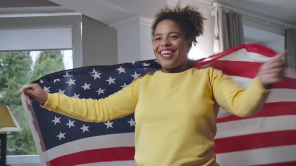 Charming African American Young Woman Wrapping in US Flag Looking Away Smiling alt