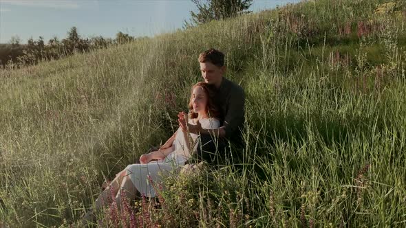 Young couple sitting on meadow and hugging