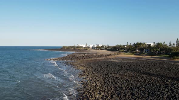 A fasting drone video showing the raw rocky coastline of the small town of Bargara located in the re alt
