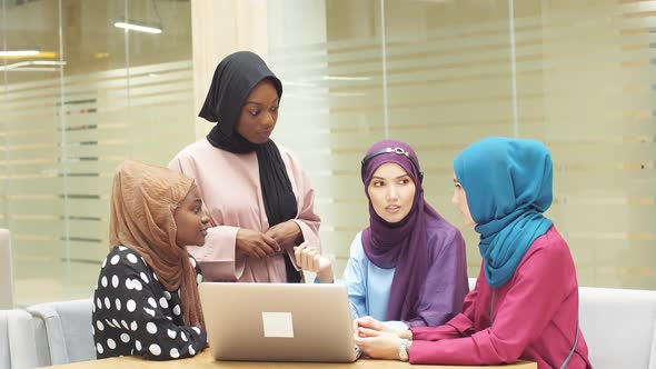 Muslim Asian and African Women in Hijabs Sit in Cafes and Make Online Purchases Using a Laptop alt