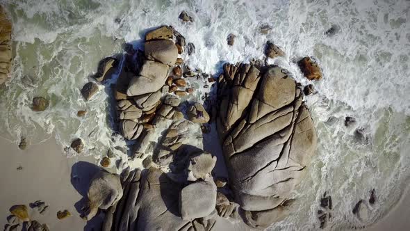Aerial view of waves crashing on granite rocks on beach, South Africa. alt