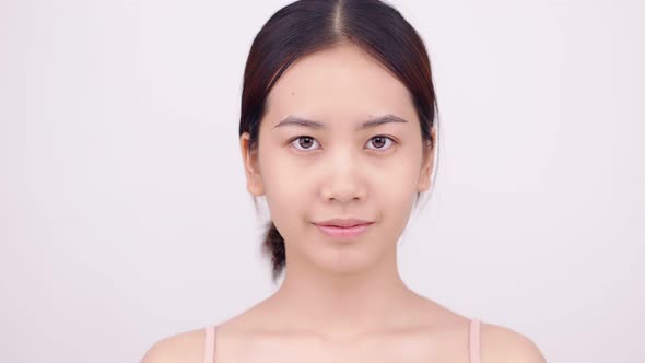 Asian girl with natural make up looking up on white background. alt
