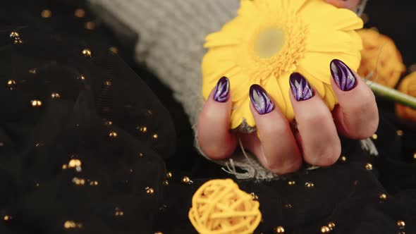 Adult Woman's Hand in Stylish Knitted Glove with Purple Manicure on Black Background alt