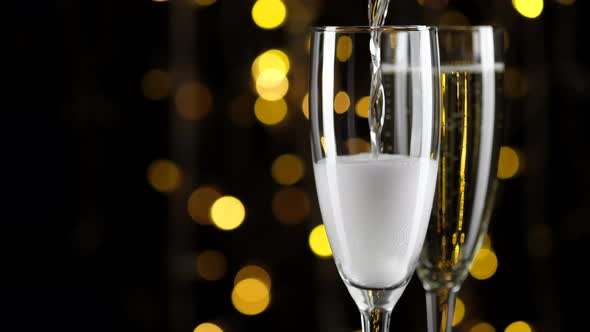 Champagne. pour champagne in glass. champagne glasses over Holiday Bokeh Blinking background alt