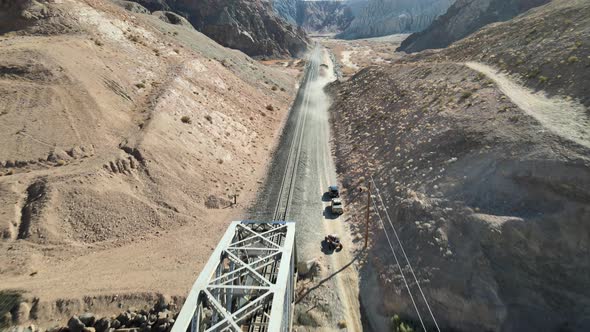 Vehicles off-roading past a creek and train truss bridge in Afton Canyon, Mojave Desert, California. alt