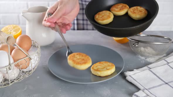 Woman hands put the curd fritter or cottage cheese pancakes on plate