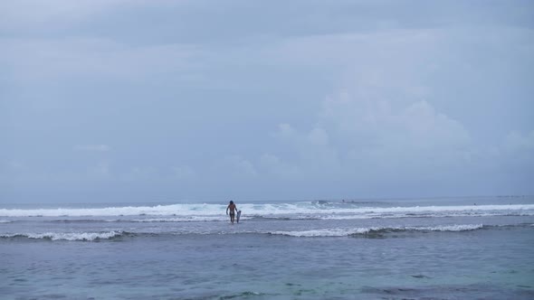 surfer with a board enters the ocean, waves in the ocean alt