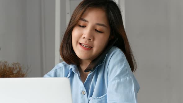 Young asian business owners using computer pc and smart phone at home office.