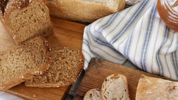 Various bread loaves with butter on wooden table alt