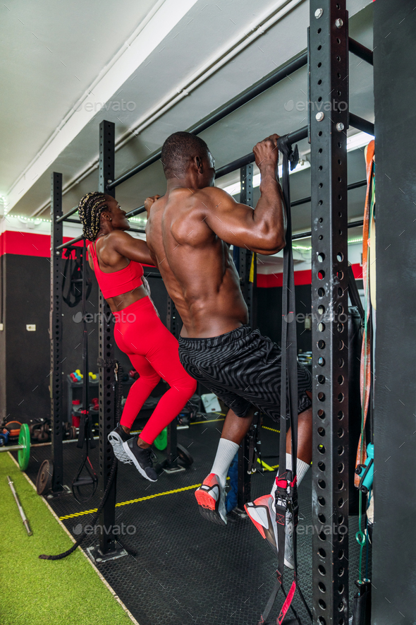 Two black bodybuilders athletes in a sports gym doing a barbell back ...