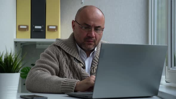 Serious Man with Glasses Opens the Laptop and Starts Typing on the Keyboard alt