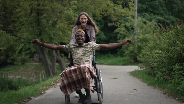 Joyful African American Man in Wheelchair Stretching Hands Smiling As Cheerful Caucasian Woman alt