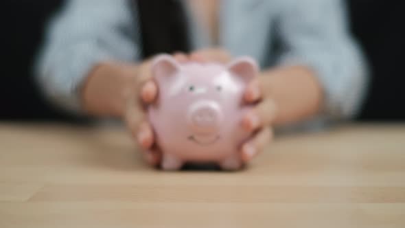 Saving money concept, Women hand hold a piggy bank on wooden table. Close up.