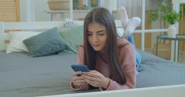 Happy Relaxed Young Woman Holding Smart Phone Looking at Cellphone Screen Using Mobile Apps for alt