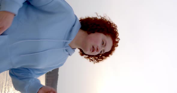 charismatic girl with curly red hair and freckles on her face runs and puts on headphones alt