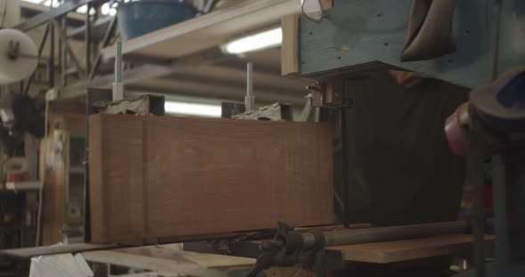 carpenter running wood through a saw machine