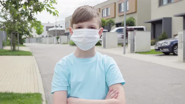 A Young Boy Puts on a Face Mask, Looks at the Camera, Takes the Mask Off in an Empty Suburban Area alt