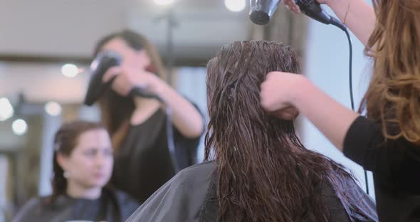 Person Dries Brunette Hair with Hairdryer in Beauty Salon