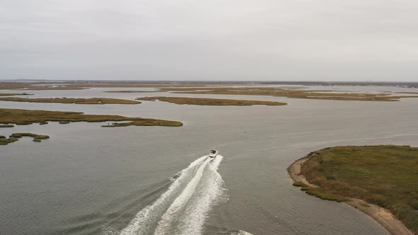 drone camera trails behind a boat, as it leaves behind a beautiful white wake in the green waters of alt