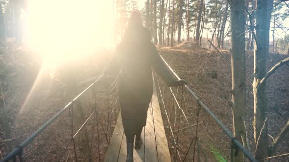 Woman Walking On Suspension Bridge. Tourist Walkway In Forest. Traveler Explore Forest.Wooden Bridge alt