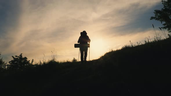 Back View Silhouette of Walking Man with Backpack on the Mountain alt