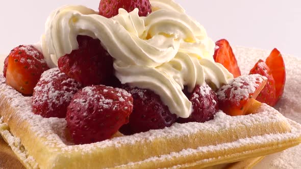 Belgian waffles with strawberry, whipped cream and powdered sugar on a plate alt
