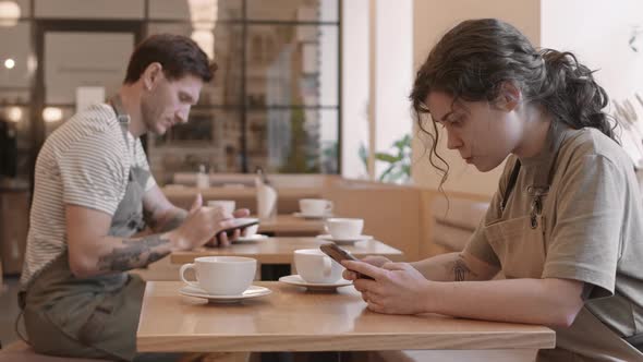 Restaurant Employees Using Smartphones by Tables alt