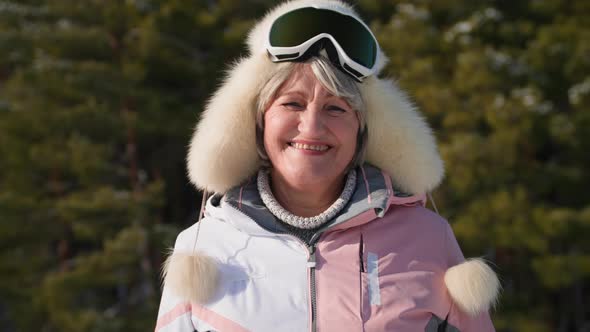 Portrait of Happy Elderly Woman in a Hat and Ski Goggles Leads an Active Lifestyle Relaxing on a
