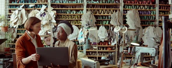 Women Working on Laptop and Talking in Shoemaking Workshop alt