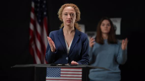 Blurred Sign Language Translator Showing Nuts Gesture and Facepalm Leaving As Politician Woman alt