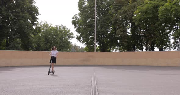 Smiling millennial woman skateboarding in the skatepark, going around a radical skate bowl alt