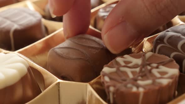 Hand-picking one chocolate from box of  many different 4K 2160p 30fps UltraHD footage - Woman chosin alt