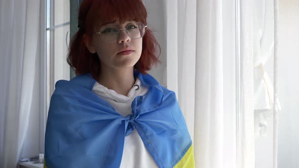 Young redhead ukrainian teen girl with flag near window