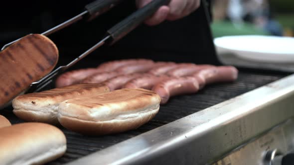 Person Turning Sausages on Grill