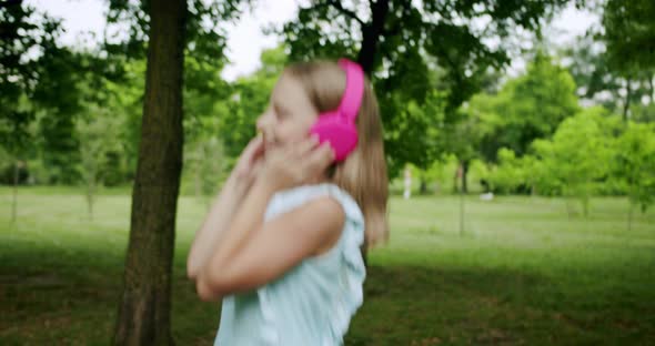 Happy Child Girl in Headphones Dancing and Jumping While Listening to the Music alt