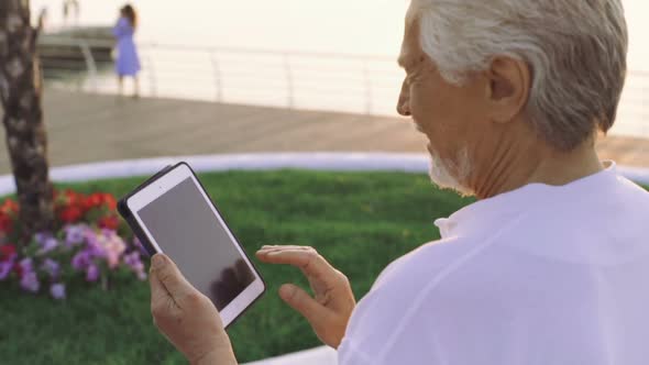 Portrait of Retirement Handsome Senior Man Using Tablet Computer on Seafront alt