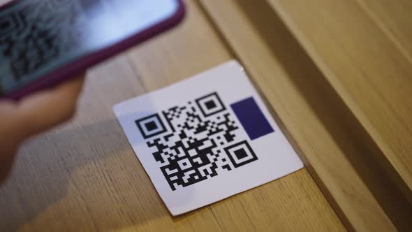 Closeup QR Code on Table with Female Hand Scanning Online Menu with Smartphone App in Restaurant alt