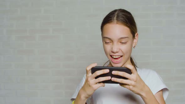 Teenager Girl Having Fun While Playing Video Game Touching Smartphone Screen alt