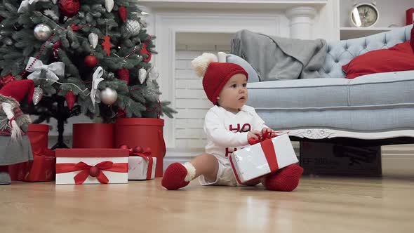 Smiling Baby in Christmas Clothes Sitting on the Wooden Floor and Playing alt