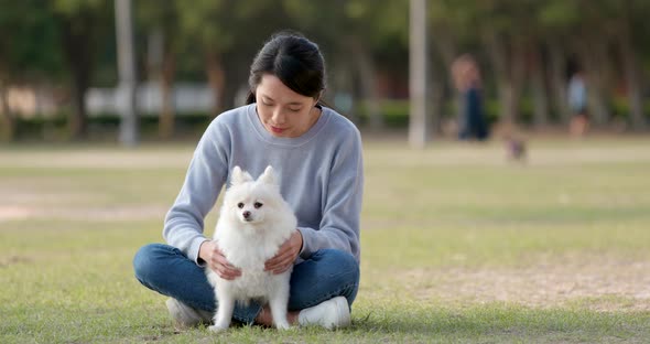 Woman playing with her Pomeranian dog at outdoor park alt
